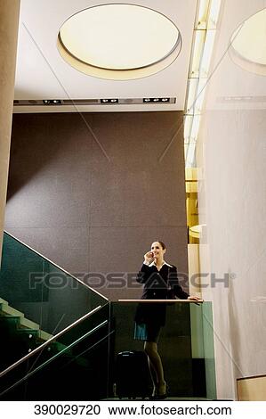 Businesswoman standing on a staircase and talking on a mobile phone View Large Photo Image Stock Image - Businesswoman standing on a staircase and talking on a mobile phone. Fotosearch