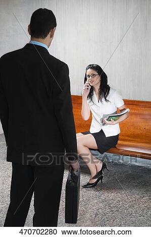 Businesswoman talking on a mobile phone in front of a businessman View Large Photo Image Stock Image - Businesswoman talking on a mobile phone in front of a businessman. Fotosearch