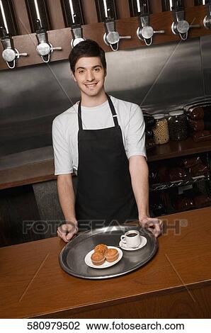 Cafe owner standing at a cafe counter and smiling View Large Photo Image Stock Image - Cafe owner standing at a cafe counter and smiling. Fotosearch
