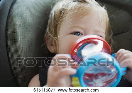 Stock Photo - Close-up of a baby girl drinking water from a baby bottle. Fotosearch