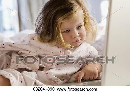 Close-up of a baby girl leaning on the bed and working on a laptop View Large Photo Image Stock Image - Close-up of a baby girl leaning on the bed and working on a laptop. Fotosearch