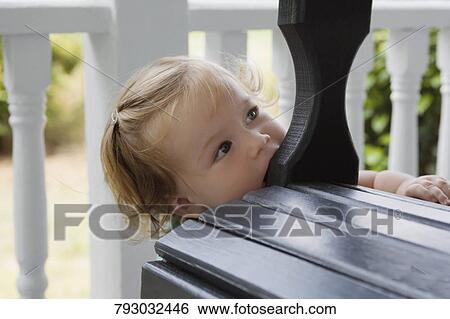 Close-up of a baby girl playing with a bench View Large Photo Image Stock Photograph - Close-up of a baby girl playing with a bench. Fotosearch