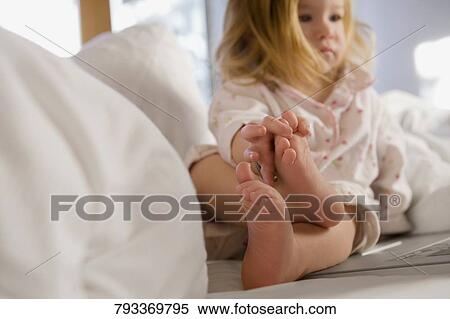 Close-up of a baby girl sitting on the bed and looking at a laptop View Large Photo Image Stock Photography - Close-up of a baby girl sitting on the bed and looking at a laptop. Fotosearch
