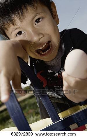 Close-up of a boy holding an egg View Large Photo Image Stock Photo - Close-up of a boy holding an egg. Fotosearch