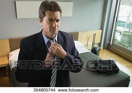 Picture - Close-up of a businessman adjusting his tie. Fotosearch