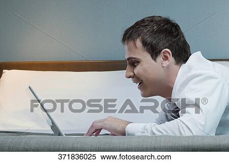 Close-up of a businessman working on a laptop and smiling View Large Photo Image Stock Photography - Close-up of a businessman working on a laptop and smiling. Fotosearch