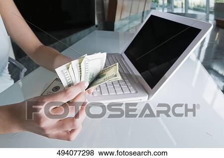 Stock Photo - Close-up of a businesswoman's hand counting US paper currency. Fotosearch