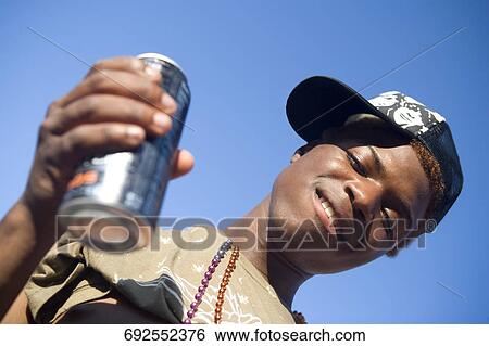 Close-up of a gay man holding a can and smiling View Large Photo Image Stock Photograph - Close-up of a gay man holding a can and smiling. Fotosearch