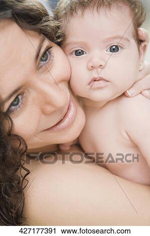 Stock Image - Close-up of a mature woman carrying her newborn baby girl. Fotosearch