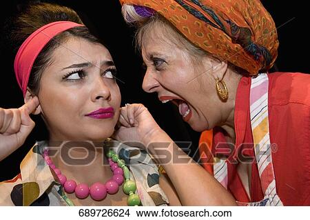 Close-up of a mature woman shouting and her daughter sticking fingers in her ears View Large Photo Image Picture - Close-up of a mature woman shouting and her daughter sticking fingers in her ears. Fotosearch