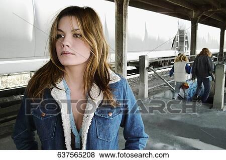 Stock Photo - Close-up of a mid adult woman standing at a railroad station platform. Fotosearch