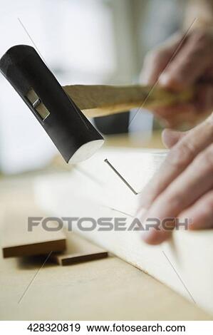 Close-up of a person's hand hammering a nail View Large Photo Image Stock Photo - Close-up of a person's hand hammering a nail. Fotosearch