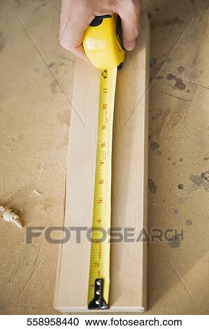 Close-up of a person's hand measuring a wooden plank View Large Photo Image Stock Image - Close-up of a person's hand measuring a wooden plank. Fotosearch
