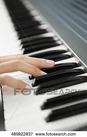 Close-up of a person's hand playing a piano View Large Photo Image Stock Photo - Close-up of a person's hand playing a piano. Fotosearch