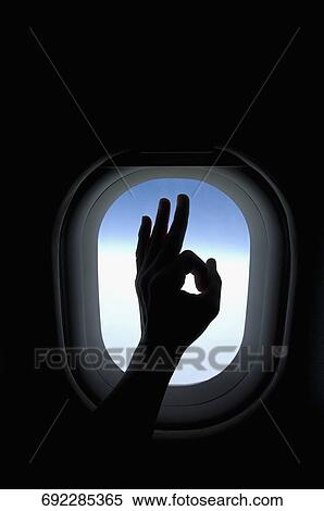 Stock Photography - Close-up of a person's hand showing ok sign in an airplane. Fotosearch