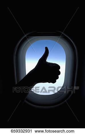Stock Image - Close-up of a person's hand showing thumbs up sign in an airplane. Fotosearch