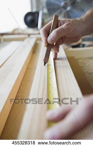 Close-up of a person's hands measuring a wooden plank View Large Photo Image Stock Photo - Close-up of a person's hands measuring a wooden plank. Fotosearch