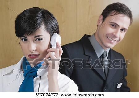 Close-up of a receptionist talking on the telephone and a businessman standing behind her View Large Photo Image Stock Image - Close-up of a receptionist talking on the telephone and a businessman standing behind her. Fotosearch