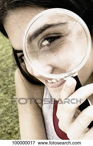 Close-up of a teenage girl looking through a magnifying glass View Large Photo Image Stock Photo - Close-up of a teenage girl looking through a magnifying glass. Fotosearch