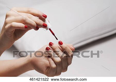 Stock Image - Close-up of a woman's hand applying nail polish. Fotosearch