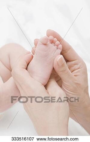 Close-up of a woman's hand holding her baby's legs View Large Photo Image Stock Photo - Close-up of a woman's hand holding her baby's legs. Fotosearch