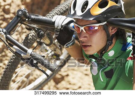 Close-up of a young man carrying a mountain bike on his shoulders View Large Photo Image Stock Photography - Close-up of a young man carrying a mountain bike on his shoulders. Fotosearch