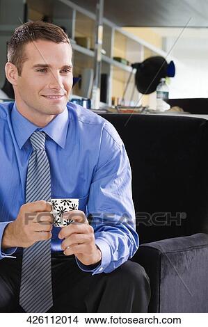 Close-up of a young man having a cup of tea and smiling View Large Photo Image Picture - Close-up of a young man having a cup of tea and smiling. Fotosearch