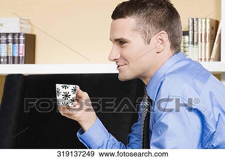 Close-up of a young man having a cup of tea and smiling View Large Photo Image Stock Photo - Close-up of a young man having a cup of tea and smiling. Fotosearch