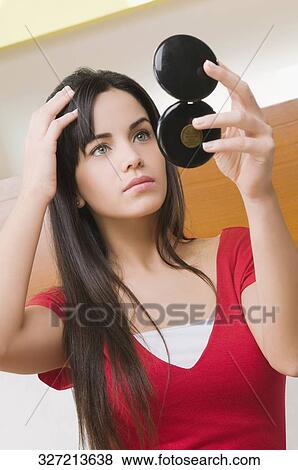 Stock Photo - Close-up of a young woman adjusting her hair. Fotosearch