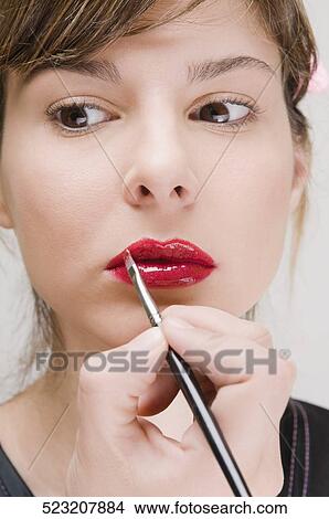 Close-up of a young woman applying lipstick View Large Photo Image Picture - Close-up of a young woman applying lipstick. Fotosearch