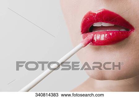 Close-up of a young woman applying lipstick View Large Photo Image Stock Image - Close-up of a young woman applying lipstick. Fotosearch
