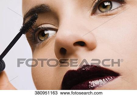 Close-up of a young woman applying mascara View Large Photo Image Stock Image - Close-up of a young woman applying mascara. Fotosearch