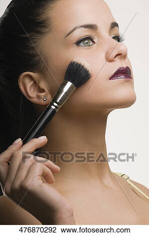 Stock Image - Close-up of a young woman applying make-up. Fotosearch