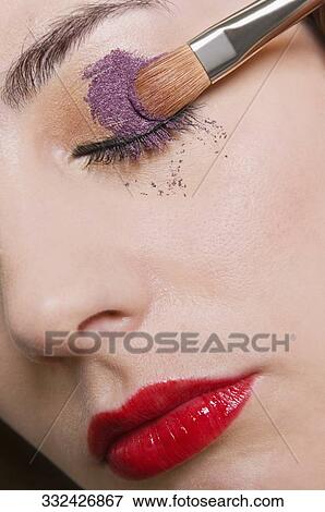 Close-up of a young woman applying eyeshadow View Large Photo Image Stock Photo - Close-up of a young woman applying eyeshadow. Fotosearch