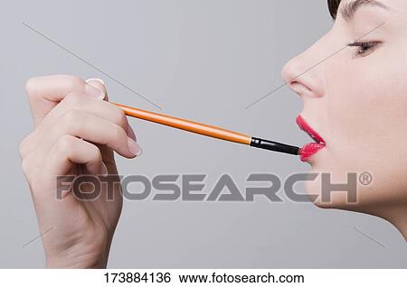 Stock Photograph - Close-up of a young woman applying lipstick. Fotosearch