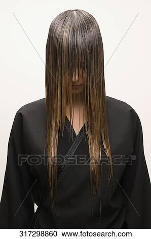 Stock Image - Close-up of a young woman covering her face with wet hair. Fotosearch