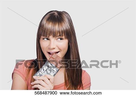 Close-up of a young woman eating a chocolate View Large Photo Image Stock Image - Close-up of a young woman eating a chocolate. Fotosearch