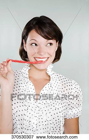 Stock Photo - Close-up of a young woman eating licorice candy. Fotosearch