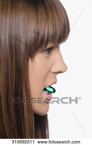 Close-up of a young woman holding a pill in her mouth View Large Photo Image Stock Image - Close-up of a young woman holding a pill in her mouth. Fotosearch
