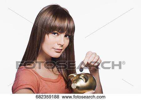 Close-up of a young woman inserting a coin into a piggy bank View Large Photo Image Stock Photo - Close-up of a young woman inserting a coin into a piggy bank. Fotosearch