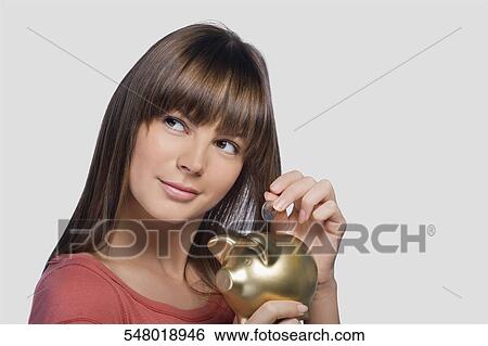 Close-up of a young woman inserting a coin into a piggy bank View Large Photo Image Stock Photograph - Close-up of a young woman inserting a coin into a piggy bank. Fotosearch