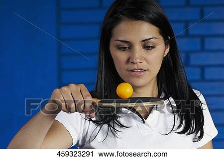 Stock Image - Close-up of a young woman playing with a table tennis racket and a ball. Fotosearch