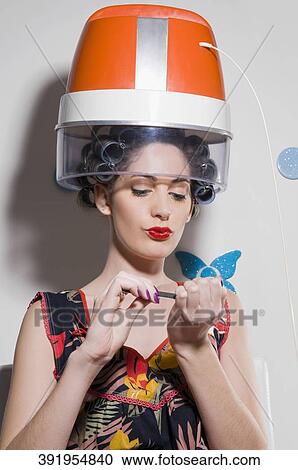 Close-up of a young woman sitting under hair dryer View Large Photo Image Stock Image - Close-up of a young woman sitting under hair dryer. Fotosearch