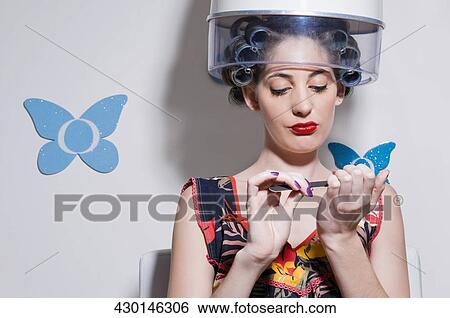 Close-up of a young woman sitting under hair dryer View Large Photo Image Stock Photograph - Close-up of a young woman sitting under hair dryer. Fotosearch