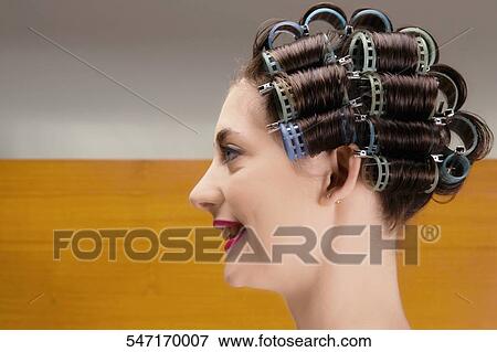 Stock Photo - Close-up of a young woman wearing hair rollers. Fotosearch