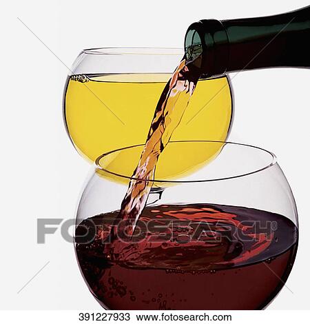 Stock Image - Close-up of red wine being poured from a bottle into a wine glass. Fotosearch