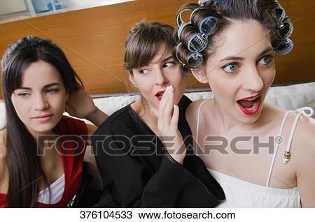 Stock Image - Close-up of three young women sitting on the couch. Fotosearch