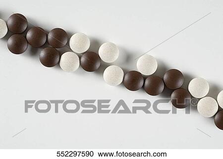 Close-up of white and brown pills in a row View Large Photo Image Stock Image - Close-up of white and brown pills in a row. Fotosearch