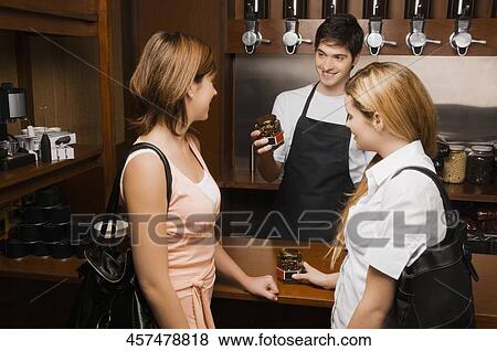 Coffee shop owner showing a coffee jar to customers View Large Photo Image Stock Photo - Coffee shop owner showing a coffee jar to customers. Fotosearch
