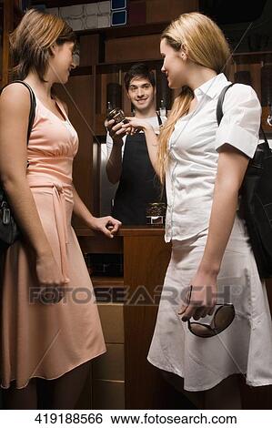 Coffee shop owner showing a coffee jar to customers View Large Photo Image Stock Photograph - Coffee shop owner showing a coffee jar to customers. Fotosearch